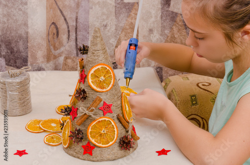 Девочка  мастерит поделку к празднику Рождества в виде необычной елки в стиле арт-деко.