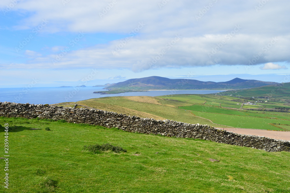 Typical Irish green landscape with coastline and small wall