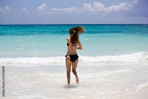 Junge sportliche Frau rennt in das Karibische Meer