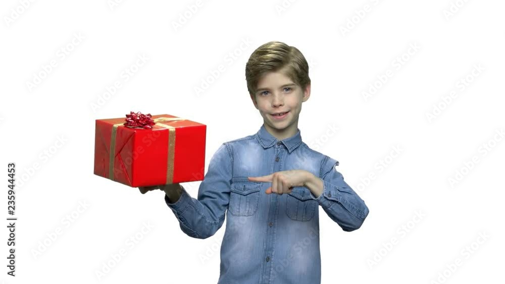 Lovely boy holding gift box. Cute stylish child pointing with finger on present box in his hand, front view. Holiday gift concept. Lovely boy holding gift box. Cute stylish child pointing with finger on present box in his hand, front view. Holiday gift concept.