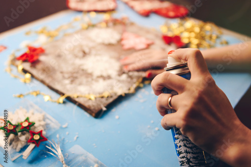 Women hands make Christmas decorations out of snow on the blue table.
