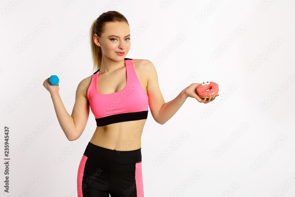 Portrait of a young girl choosing between donut and dumbbell sport isolated white background. Portrait of a young girl choosing between donut and dumbbell sport isolated white background.