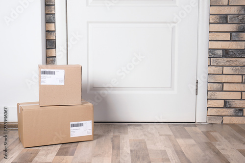Cardboard parcel boxes on floor near apartment entrance. Mockup for design