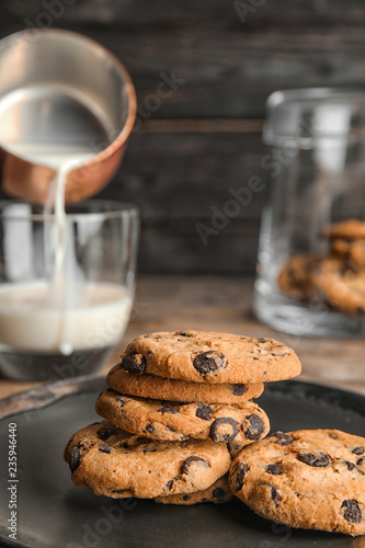Plate with tasty chocolate chip cookies on wooden table