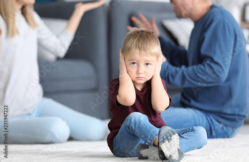 Sad little boy in room with...