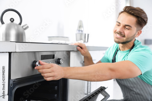 Young man baking something in oven at home