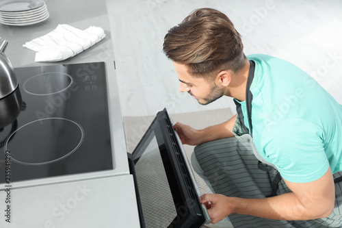 Young man baking something in oven at home