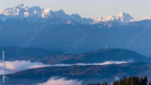 Time Lapse - Tower with moving fog on a winter day with mountains covered in snowin the background at sunrise photo