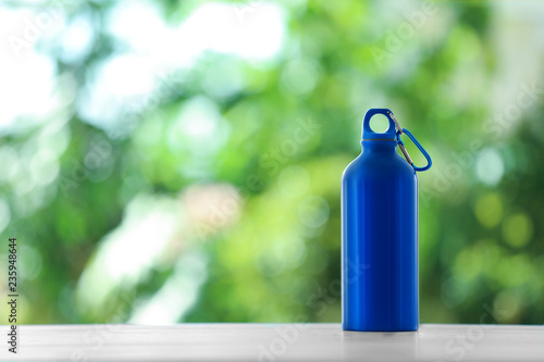 Sports water bottle on table against blurred background. Space for text