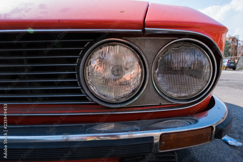 Headlight of a red retro classic car.