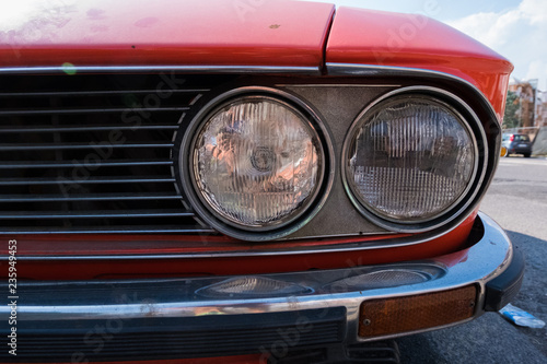 Headlight of a red retro classic car.