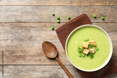 Fresh vegetable detox soup made of green peas with croutons in dish served on table, top view. Space for text photo