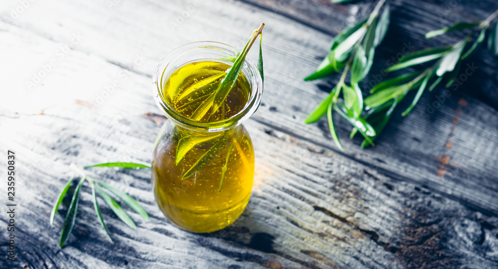 Fresh olive oil in carafe with olive twig on wooden table. Fresh olive oil in carafe with olive twig on wooden table.