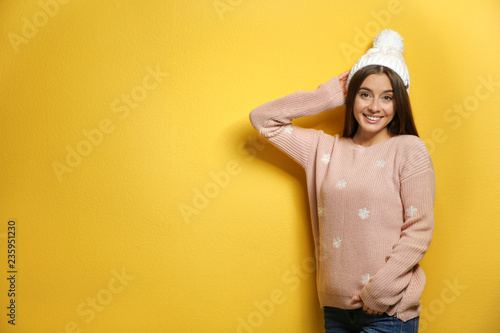 Beautiful young woman in warm sweater with hat on color background. Space for text © New Africa