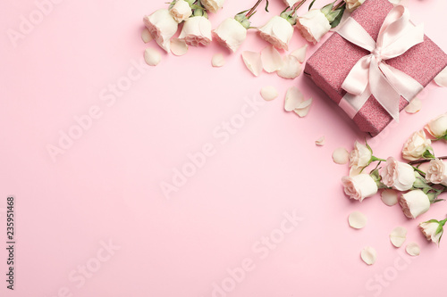 Flat lay composition with beautiful roses and gift box on color background. Space for text