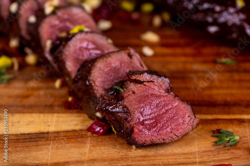 Fotografiet Venison pieces on a board with dried tomatoes