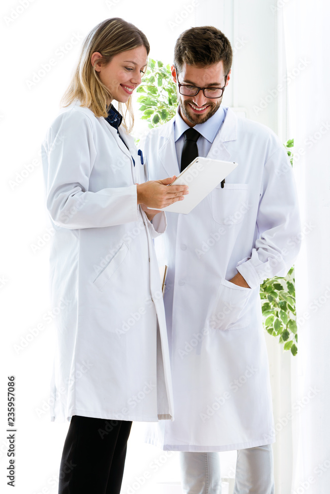 Fototapeta premium Smiling young doctors looking medical reports in digital tablet in medical office.