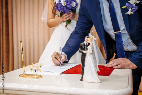 The groom signs the marriage registration documents. Young couple signing wedding documents