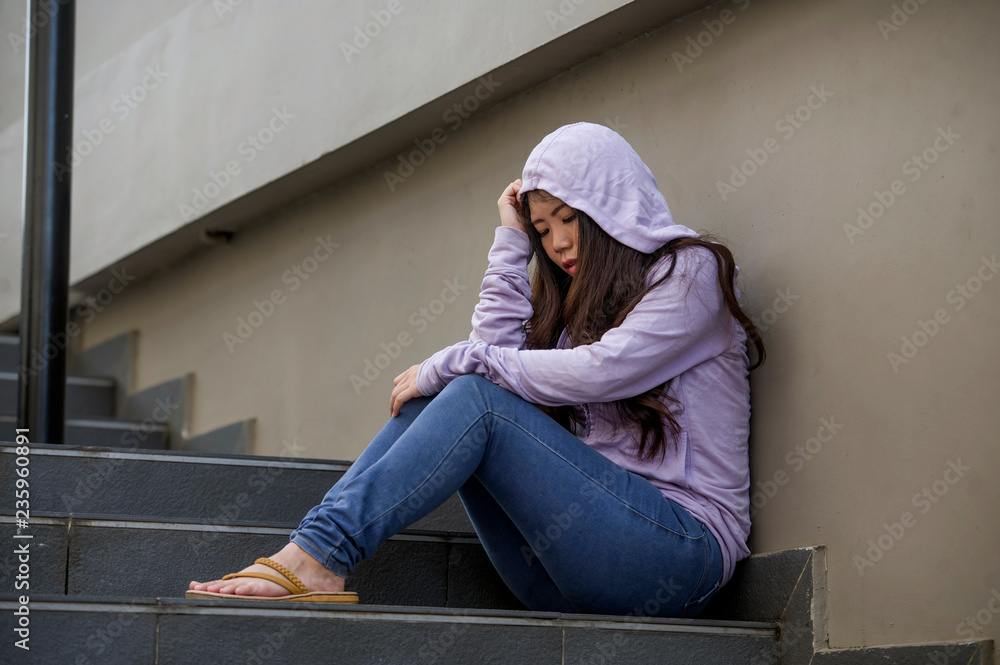 depressed Asian Chinese student woman or bullied teenager girl sitting outdoors on street staircase victim of bullying feeling scared and stressed suffering depression depressed Asian Chinese student woman or bullied teenager girl sitting outdoors on street staircase victim of bullying feeling scared and stressed suffering depression