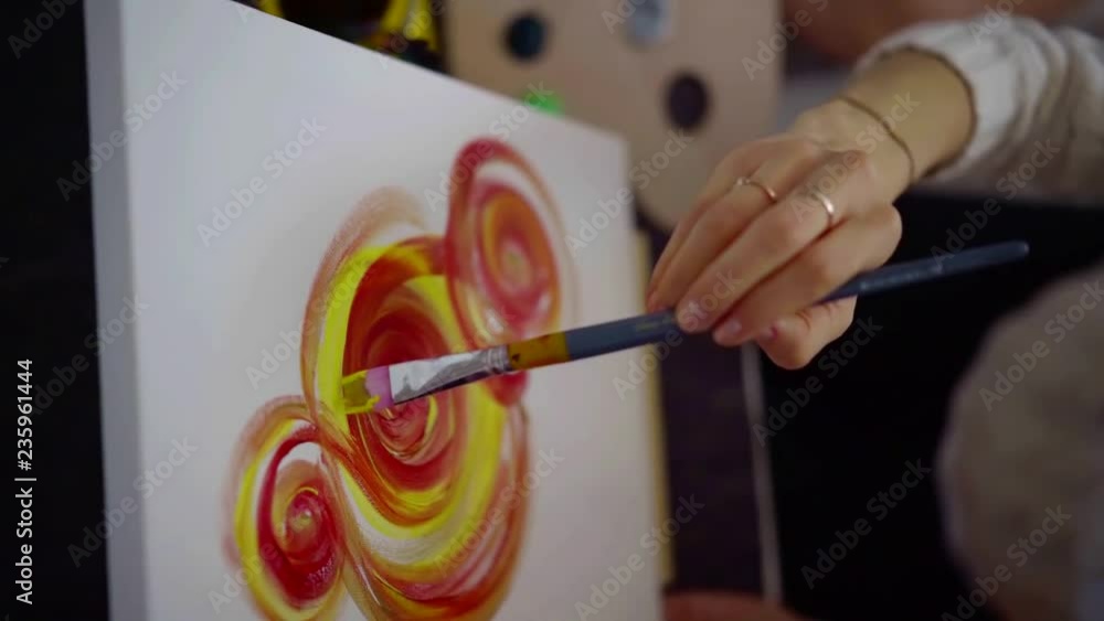 Female's artist holding a brush and drawing with paints of canvas. Female's artist holding a brush and drawing with paints of canvas.