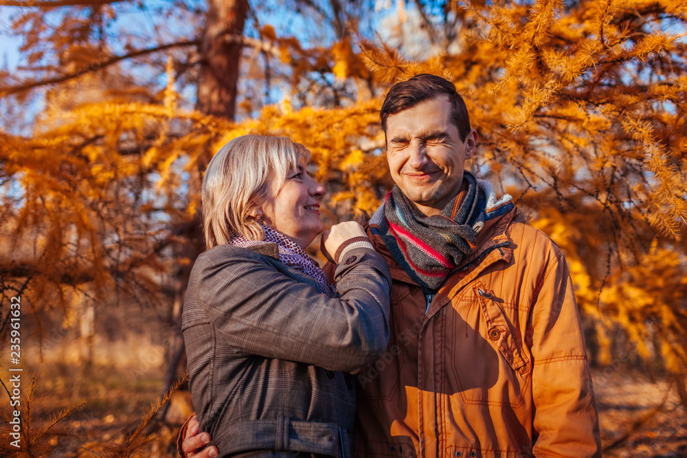 Adult son kissing his middle-aged mother in autumn park. Family values Adult son kissing his middle-aged mother in autumn park. Family values