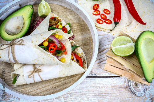 Mexican burritos closeup. Mexican restaurant fast food - wrapped burritos with pork meat, mushrooms and vegetables closeup at wooden desk photo