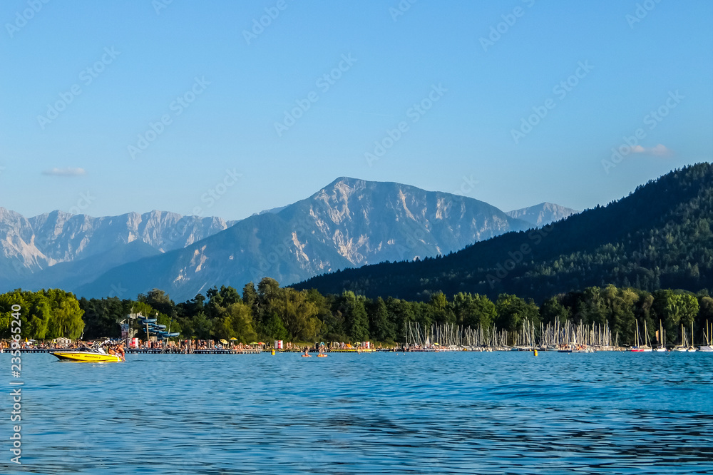 Klagenfurt, Austria. View of Worth lake with mountains and clear blue sky in background.