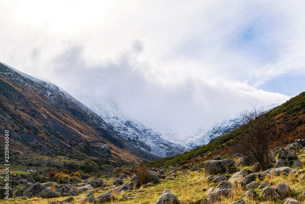 Se acerca la tormenta al valle. nubes oscuras en las cumbres nevadas contrastan con el colorido del valle en otoño