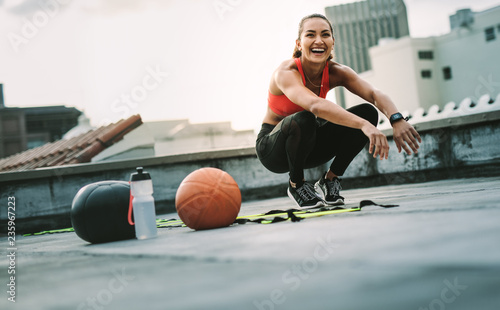 Fototapeta Naklejka Na Ścianę i Meble -  Smiling fitness woman doing sit ups on rooftop