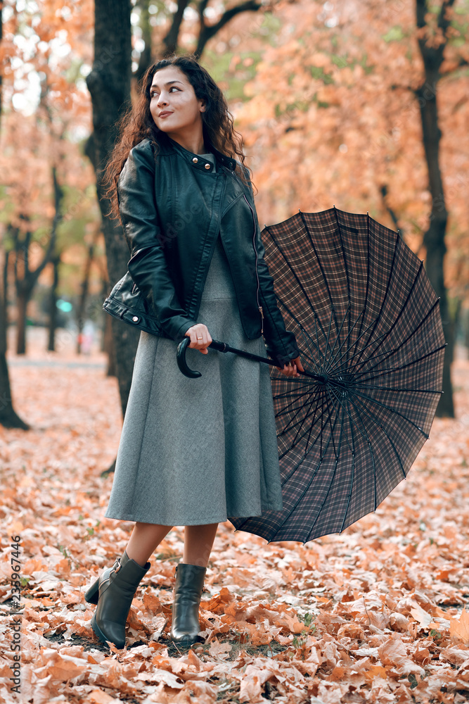 Woman with umbrella posing in autumn park. Bright yellow leaves and trees. Woman with umbrella posing in autumn park. Bright yellow leaves and trees.