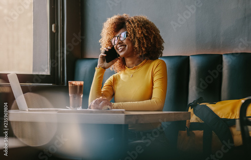 Businesswoman talking over mobile phone sitting at a restaurant