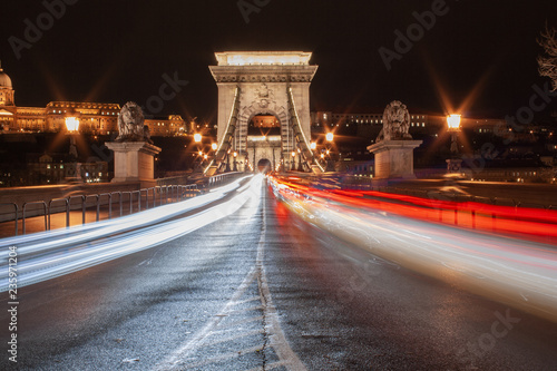 Schnelle Autos fahren vorbei - Straßenverkehr nachts auf der Kettenbrücke (Szechenyi Lanchid) in Budapest, der Hauptstadt von Ungarn