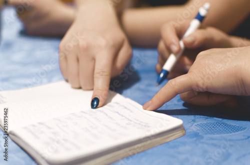 Woman is writing a notes in a notebook and plans daily schedule, close up photo.