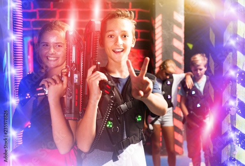 Girl and boy with laser pistols in laser tag labyrinth