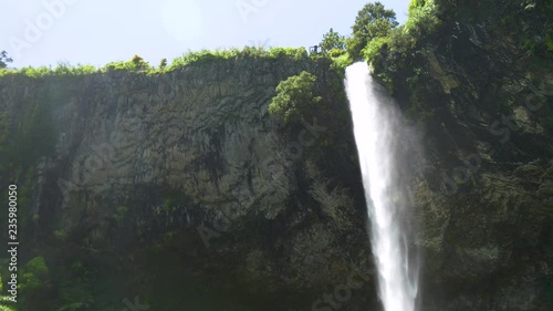 A still video of the tip of a tall and powerful waterfall that shines very bright due to the reflecting sunlight. The strong but beautiful fall of the water from 55m in 4k video quality 30fps. photo