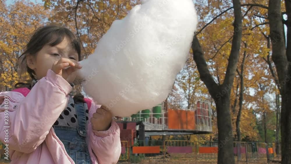 Kid with cotton candy. Little girl eating candyfloss in amusement park Kid with cotton candy. Little girl eating candyfloss in amusement park