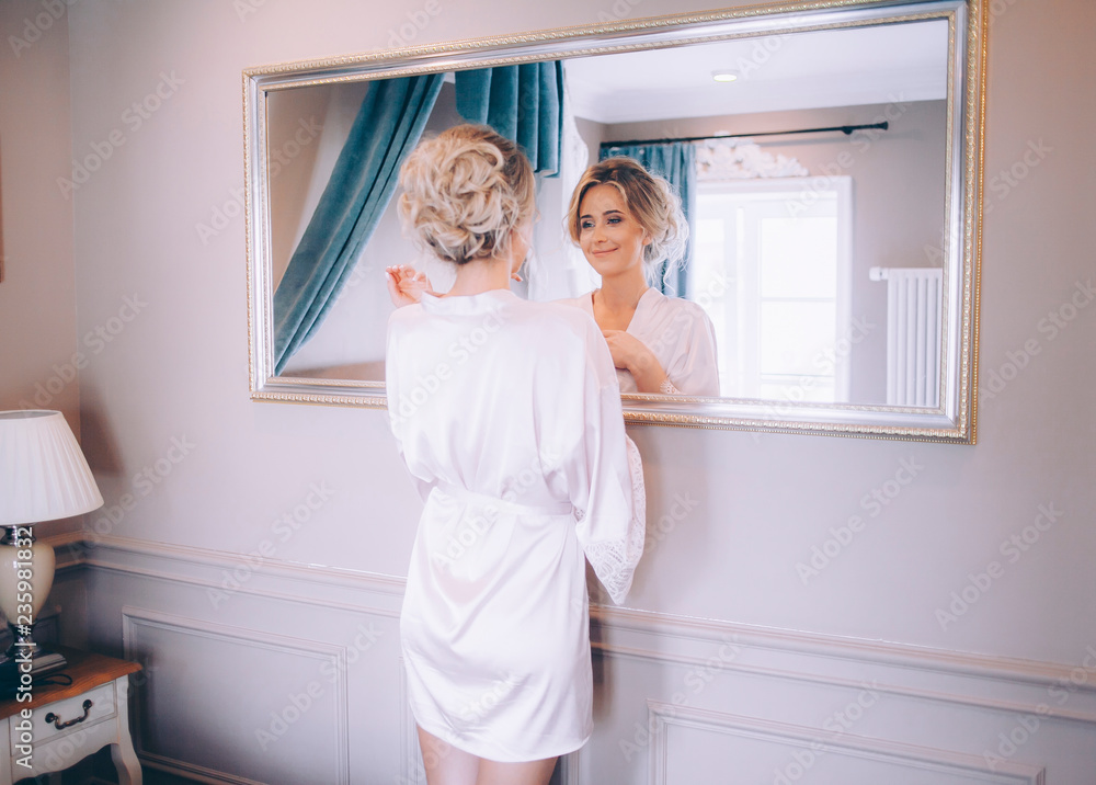 A beautiful girl is going to work in the morning, the girl is looking in the mirror while doing her hair A beautiful girl is going to work in the morning, the girl is looking in the mirror while doing her hair