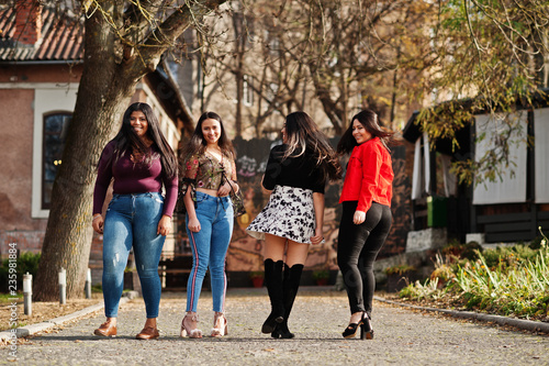 Group of four happy and pretty latino girls from Ecuador posed at street.