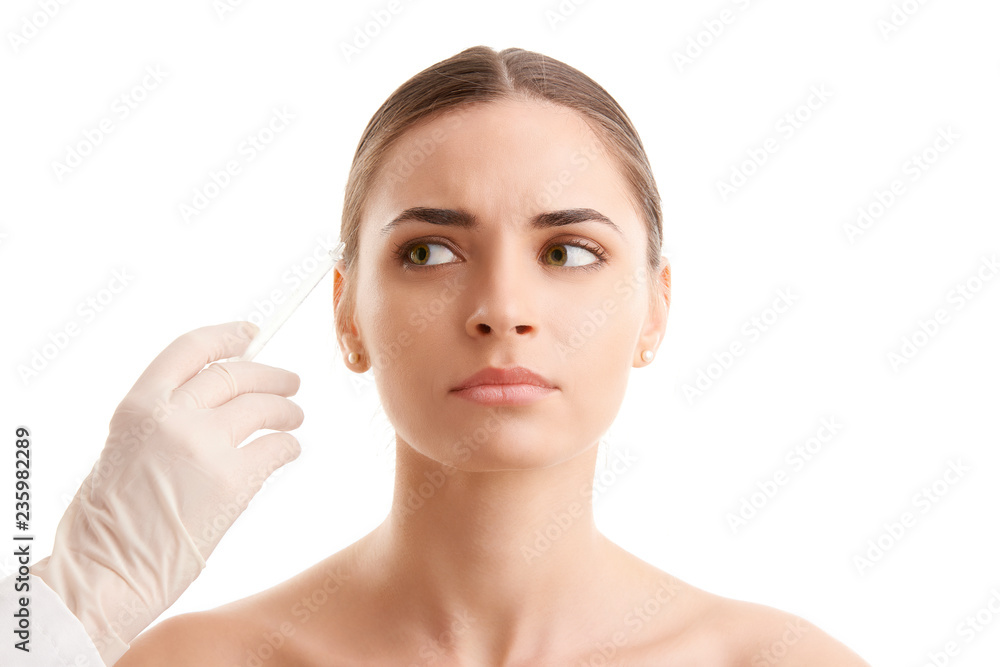 Woman at plastic surgery. Portrait of an attractive young woman receiving lip augmentation treatment. Isolated on white background.