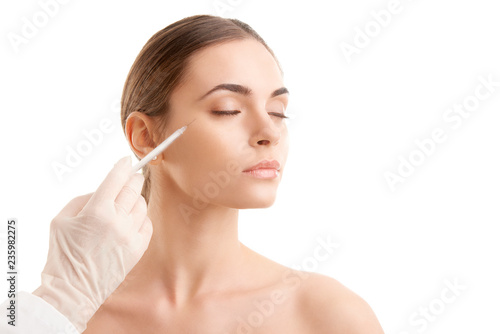 Woman at plastic surgery. Portrait of an attractive young woman receiving botox treatment. Isolated on white background.  photo