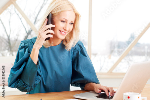 Businesswoman making call and typing on keyboard at office