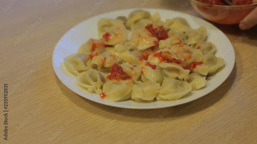 man eating dumplings with beef and tomato sauce at home in the kitchen man eating dumplings with beef and tomato sauce at home in the kitchen
