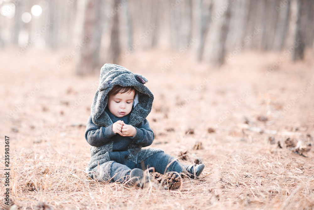 Funny baby wearinganimal suit with hood in forest. Winter season. Childhood.