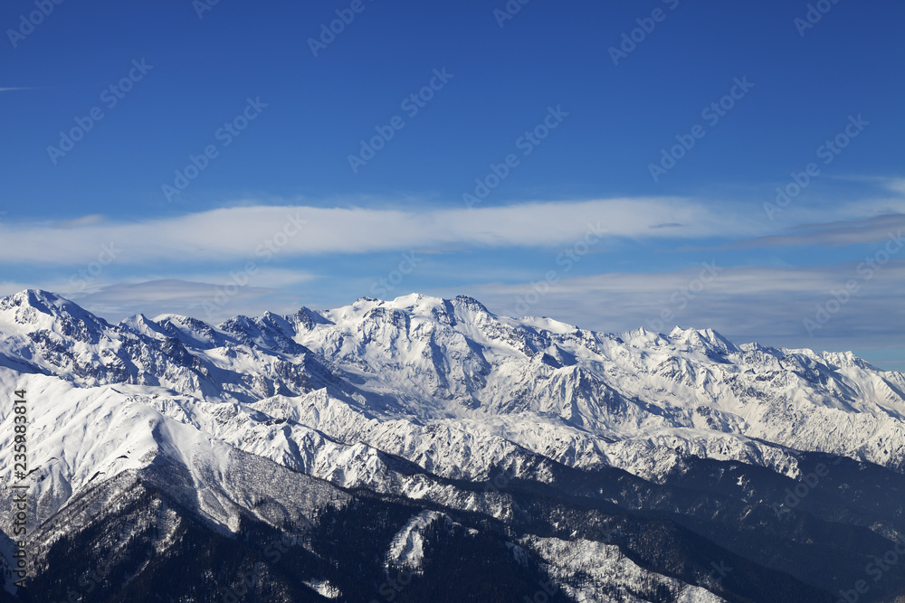 Snowy mountains and blue sky with clouds in nice sunny evening