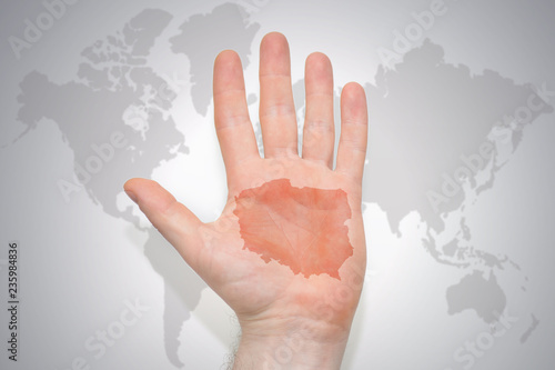 hand with map of poland on the gray world map background.