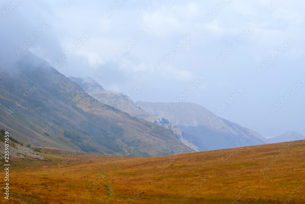 steppe plateau, alpine meadow in autumn with a foggy ridge in the distance