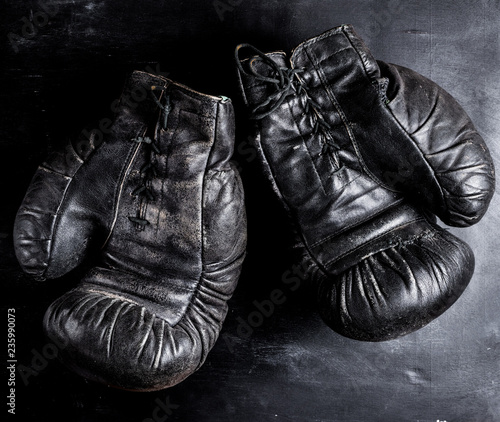pair of old leather boxing gloves with laces on a wooden background
