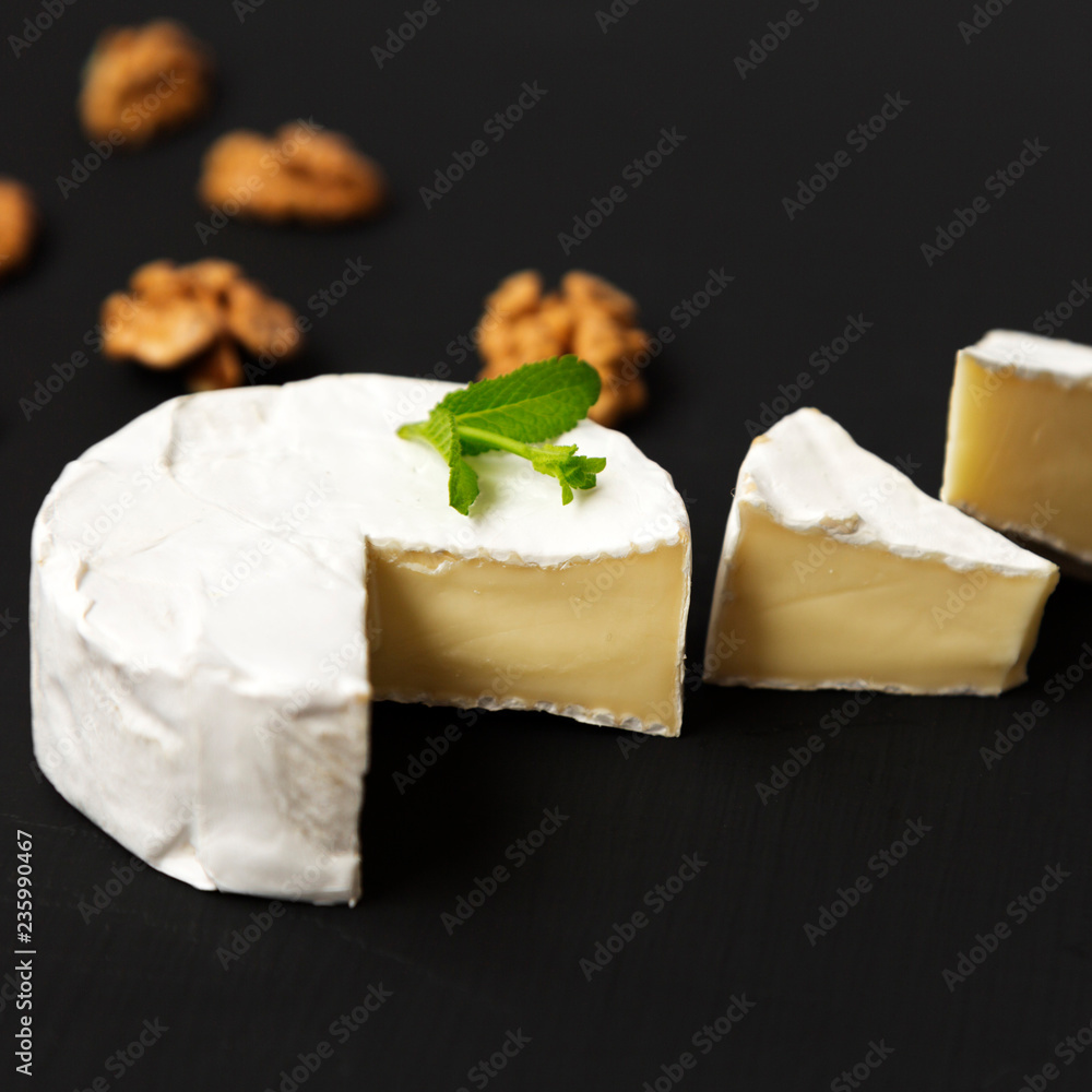 Cheese camembert or brie with walnuts on dark background. Side v