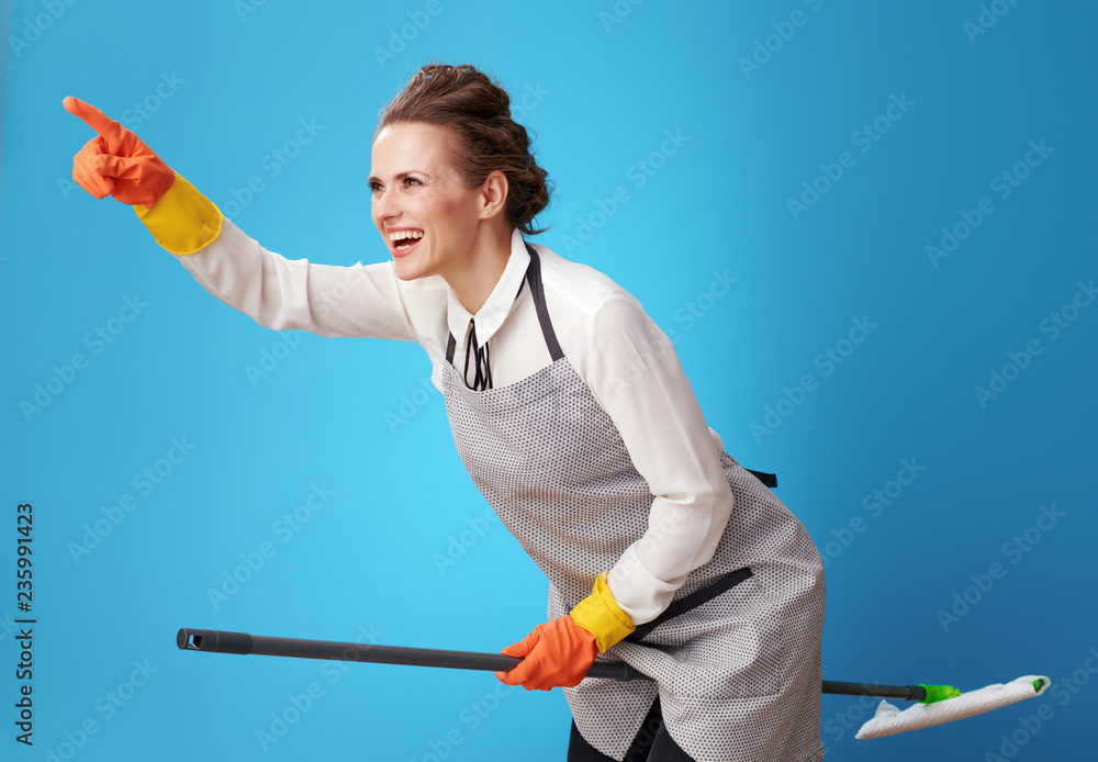 happy scrubwoman pointing at something using mop as broomstick happy scrubwoman pointing at something using mop as broomstick