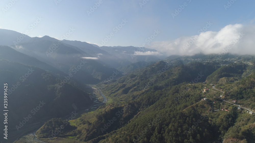 Aerial view of mountains covered forest, trees in clouds and fog. Cordillera region. Luzon, Philippines. Slopes of mountains with evergreen vegetation. Mountainous tropical landscape.